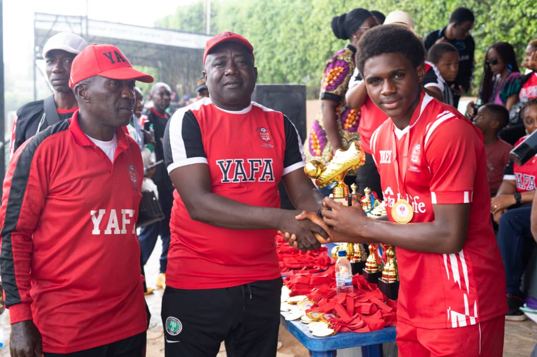 YAFA official presenting a golden boot trophy to a young winner