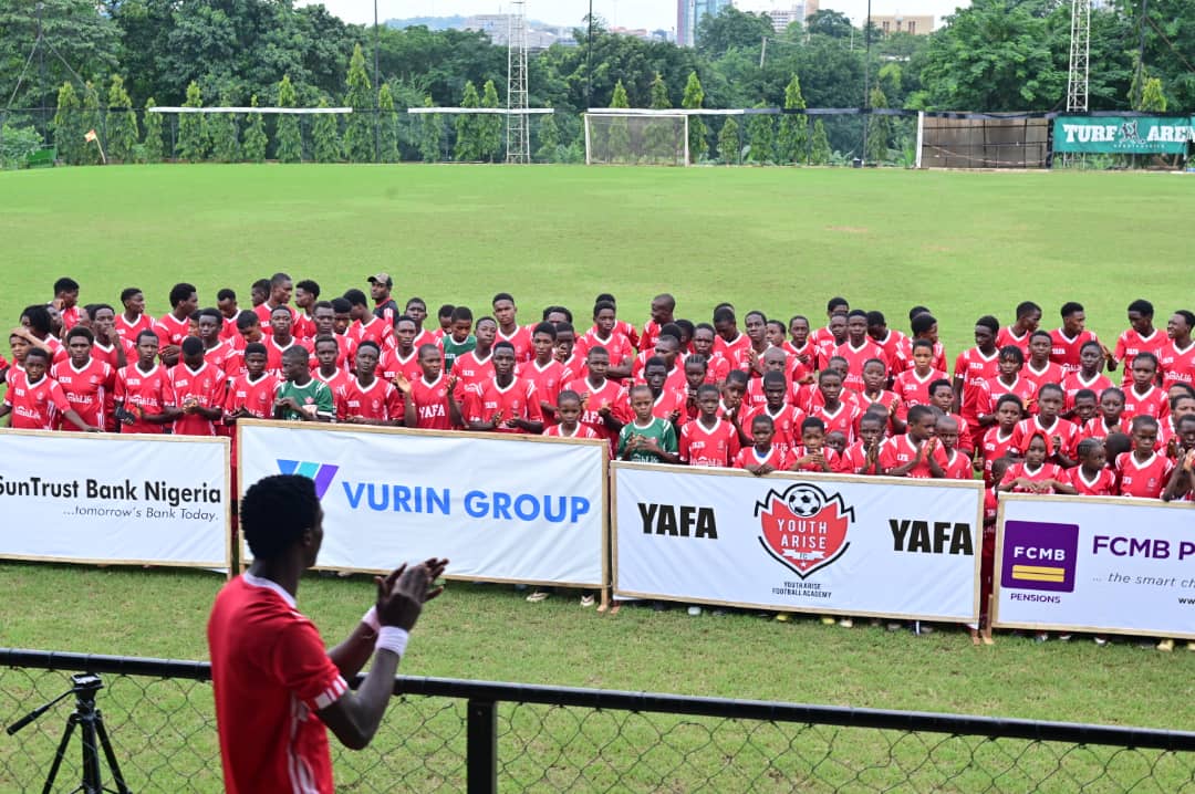 Full tournament squad behind YAFA and sponsor banners at Turf Arena