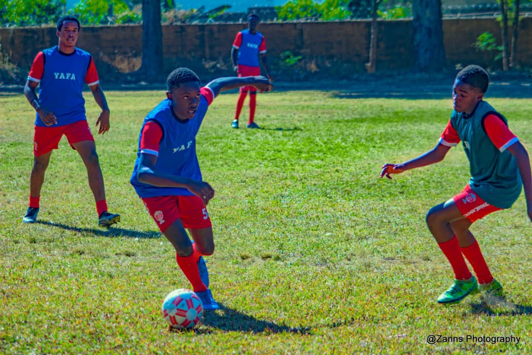 Young YAFA player driving forward with the ball in a school fixture