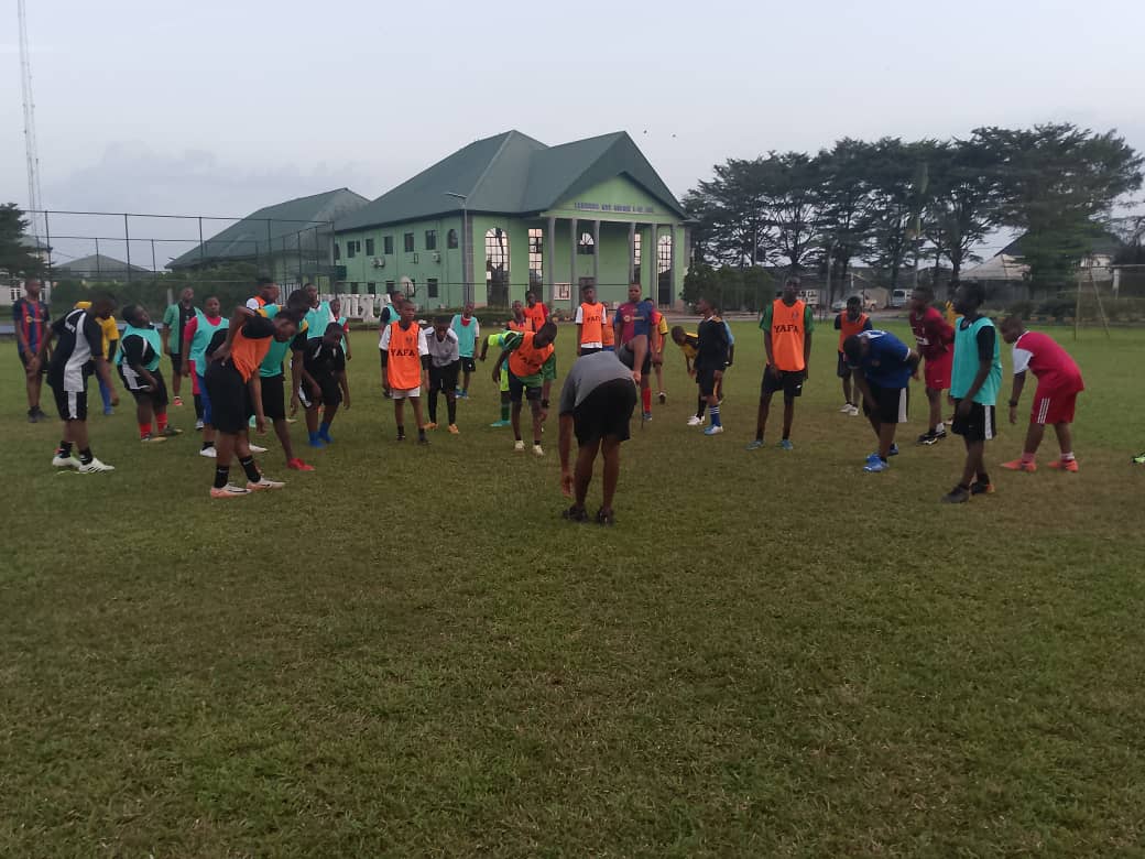 Coach leading a warm-up drill with school pupils in training bibs